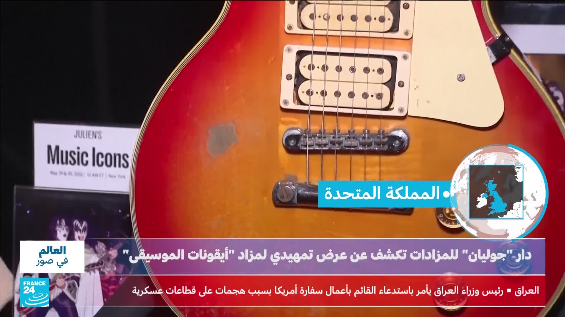 A sunburst electric guitar, likely a Les Paul, rests on display. Text on screen mentions Julien's auctions and "Music Icons," with a map of the United Kingdom visible. A sunburst electric guitar, likely a Les Paul, rests on display. Text on screen mentions Julien's auctions and "Music Icons," with a map of the United Kingdom visible.