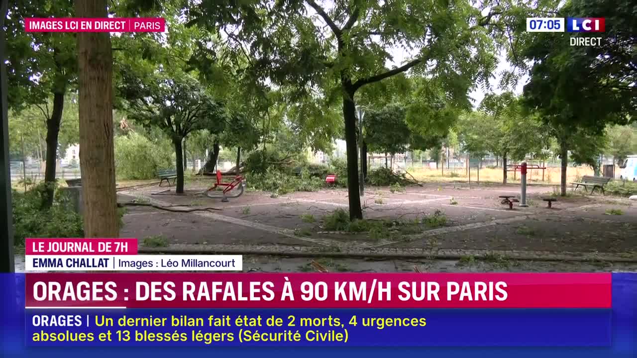 A park in Paris is strewn with fallen branches and debris. A red bicycle lies on its side, and the scene is being broadcast live on LCI.

