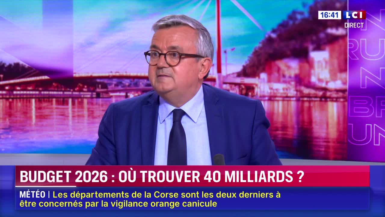 A man in a suit and tie, wearing glasses, is speaking on LCI. The lower third of the screen displays a headline about the 2026 budget, with a weather update below.
