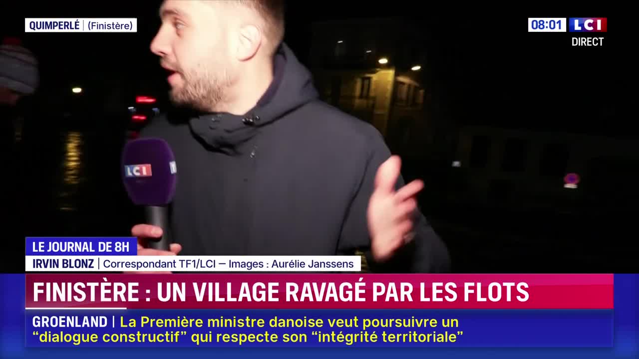 A reporter stands in front of a dark, flooded street, holding an LCI microphone. He gestures with his free hand as he speaks, recounting the devastation in Finistère.