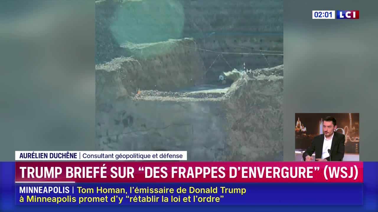A bulldozer pushes dirt at a construction site. The LCI broadcast shows a man in a suit speaking.