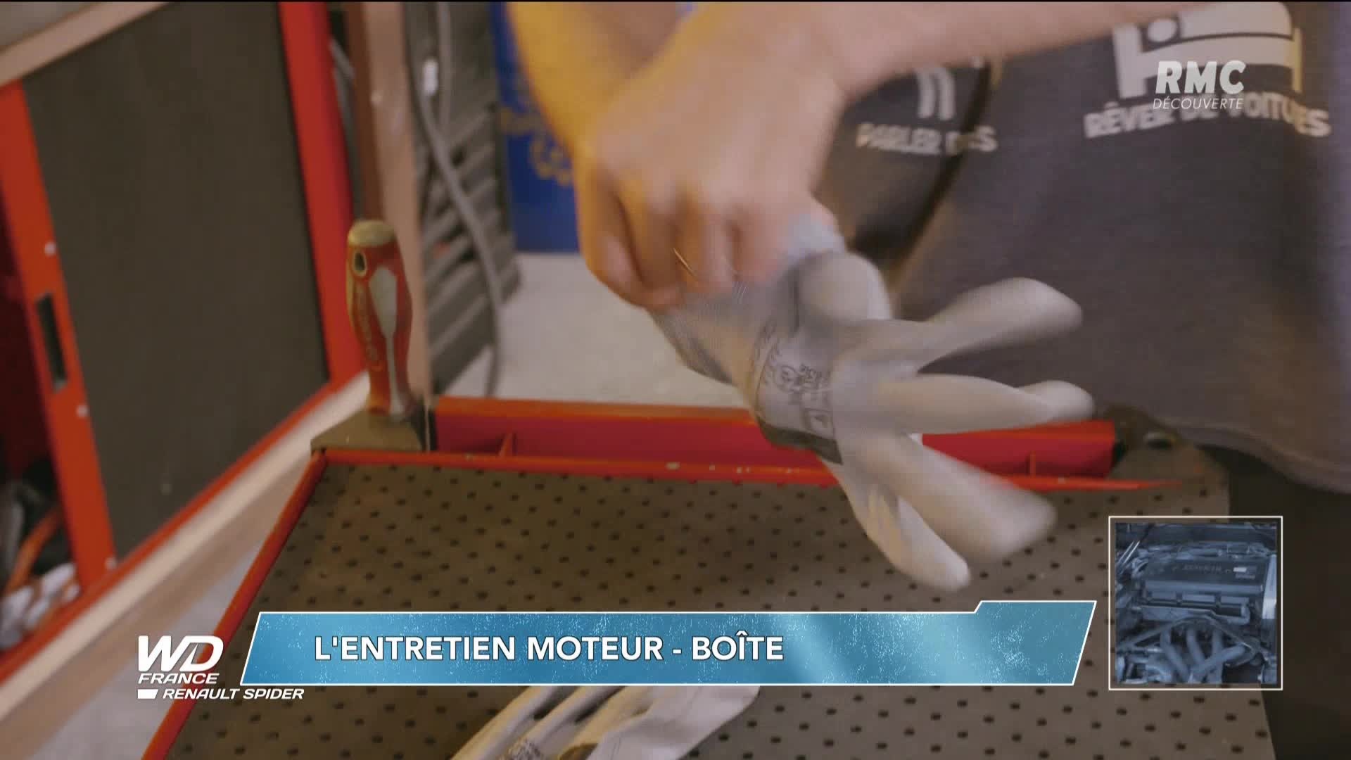 A mechanic is pulling on a work glove, preparing for a job on the Renault Spider featured on RMC Découverte. The scene is set in a workshop, with tools and equipment visible.
