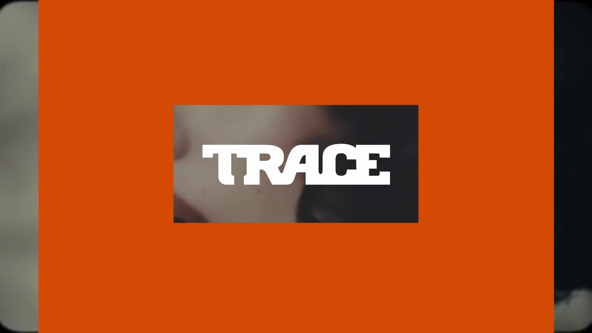 The word "TRACE" is centered in white, bold letters, partially obscuring a close-up of a face. The logo is set against a bright orange backdrop, with darker sections on either side.
