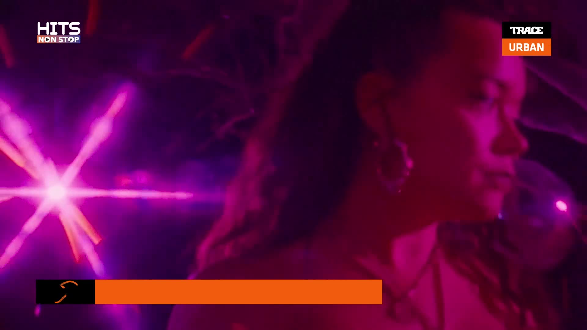 A woman's silhouette is partially visible, illuminated by bright purple and pink lights. The "TRACE URBAN" logo and "HITS NON STOP" are in the corners, and an orange banner runs across the bottom.
