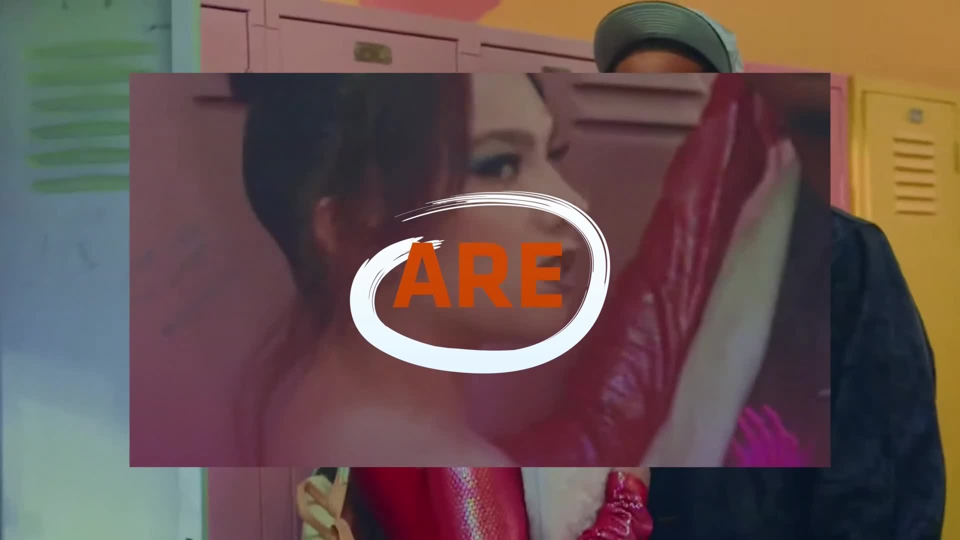 A woman in red latex leans back, her face partially obscured by the superimposed text. A man in a cap stands beside her, framed by lockers.
