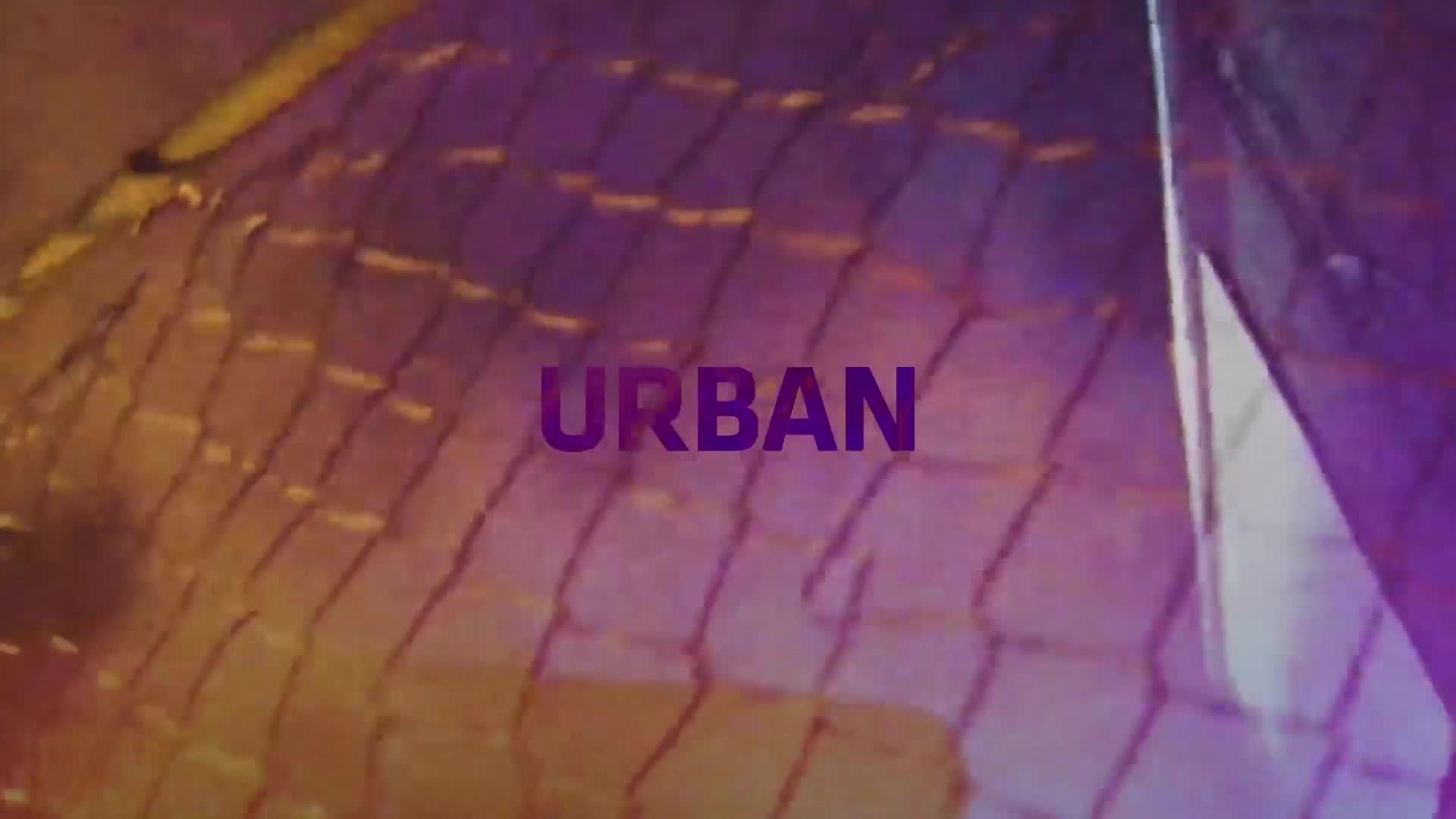 The word "URBAN" is centered in purple, superimposed over a chain-link fence. The background glows with a mix of yellow and purple light.
