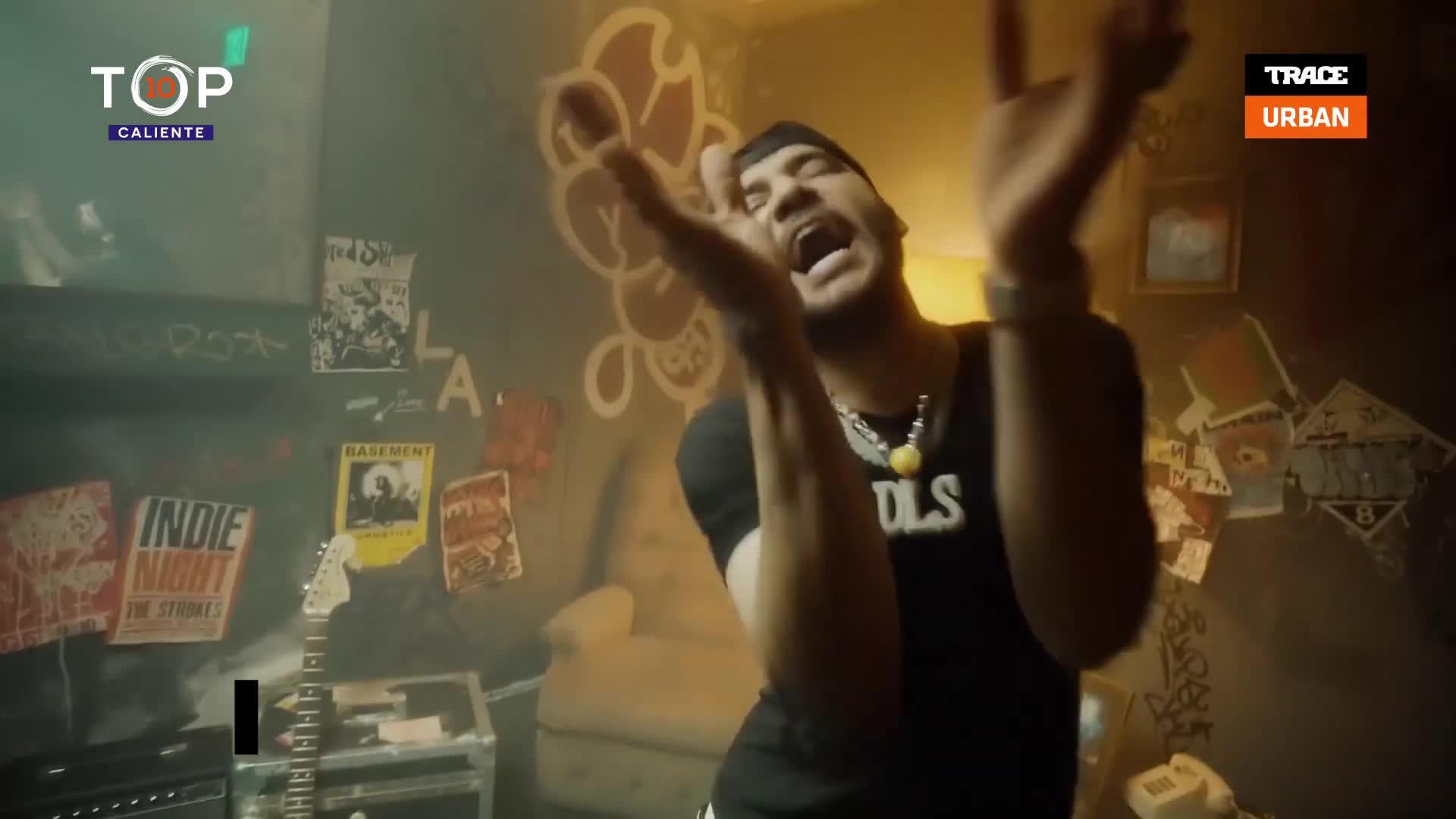 He's rapping, arms raised, in a room plastered with posters, the Trace Urban logo visible in the corner. The whole scene feels like a music video, probably from France.
