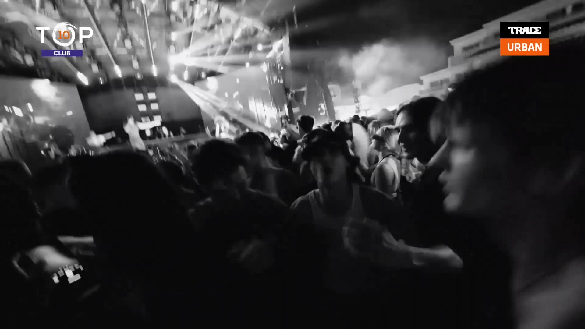 The crowd is packed tight, bodies swaying under the bright stage lights. Someone's holding up a phone, trying to capture the energy of this French club night.
