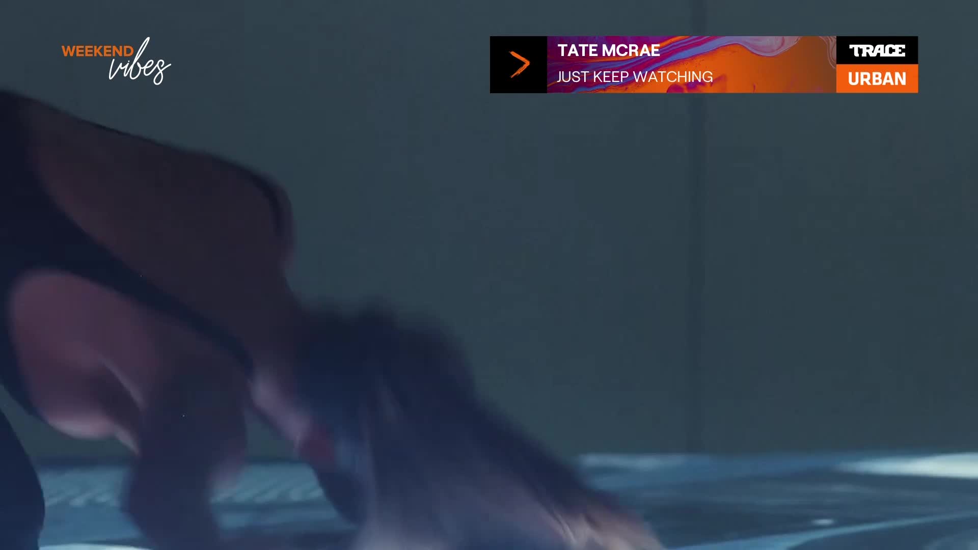 A figure is bent over, their form partially obscured by the dim lighting. The Trace Urban logo and the words "Weekend Vibes" suggest a music video on French television.
