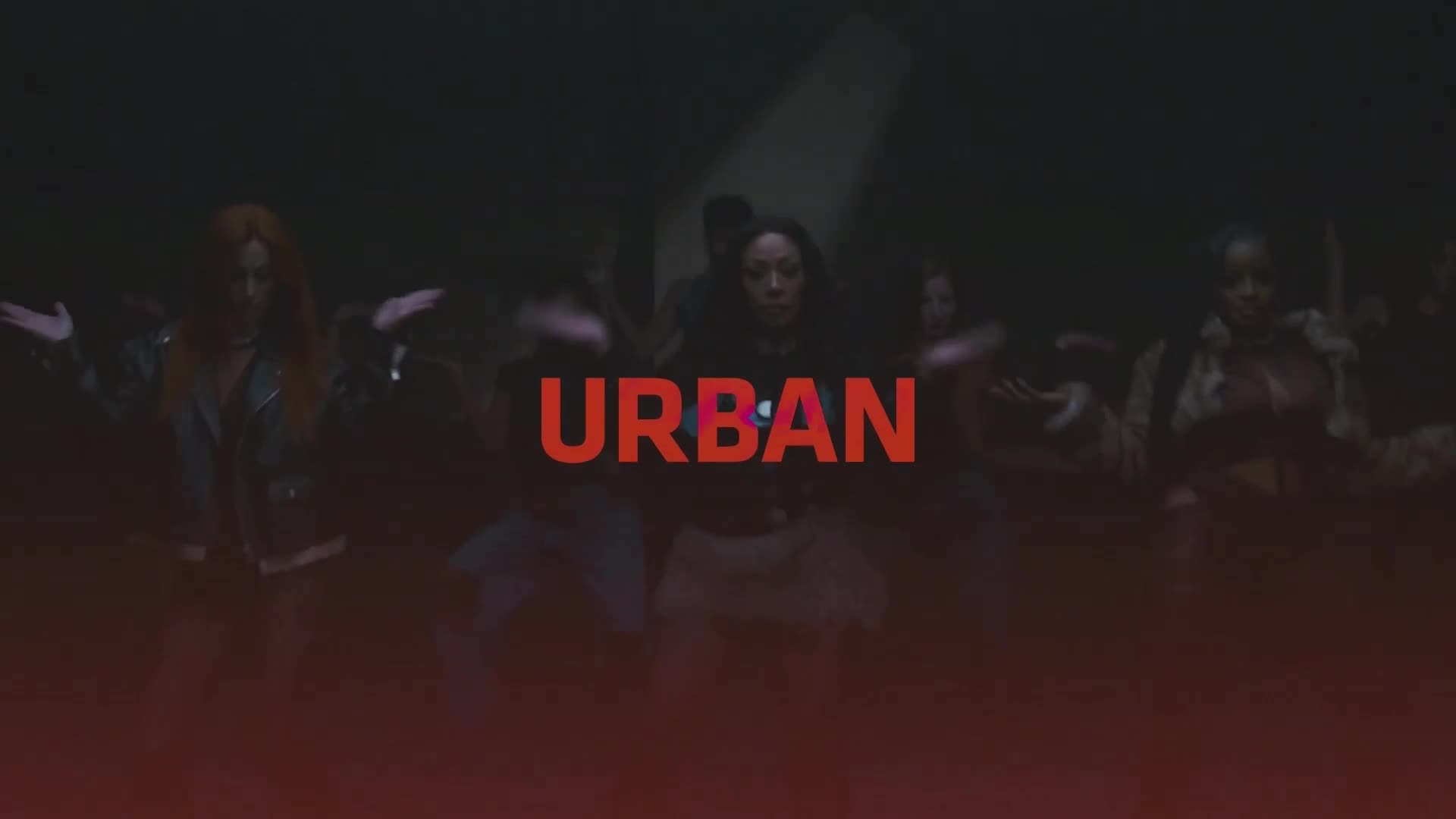 A group of dancers moves in unison under dim lights, the word "URBAN" glowing in red across the center of the stage. Their arms are outstretched, hands open, as they perform a synchronized routine. A group of dancers moves in unison under dim lights, the word "URBAN" glowing in red across the center of the stage. Their arms are outstretched, hands open, as they perform a synchronized routine.
