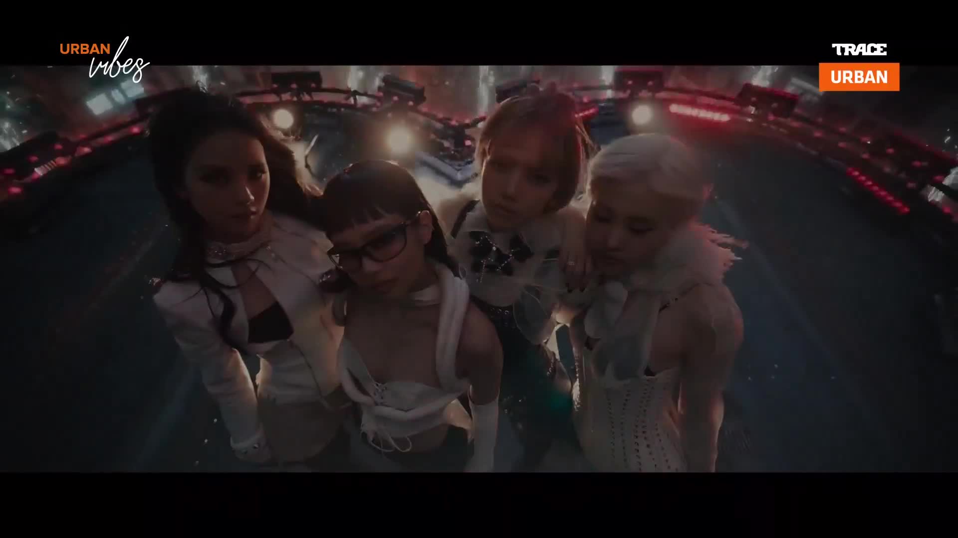 Four women in striking outfits gather close, their faces illuminated by the pulsing lights of a French urban night. A Trace Urban logo flashes in the corner, hinting at the vibrant music scene.