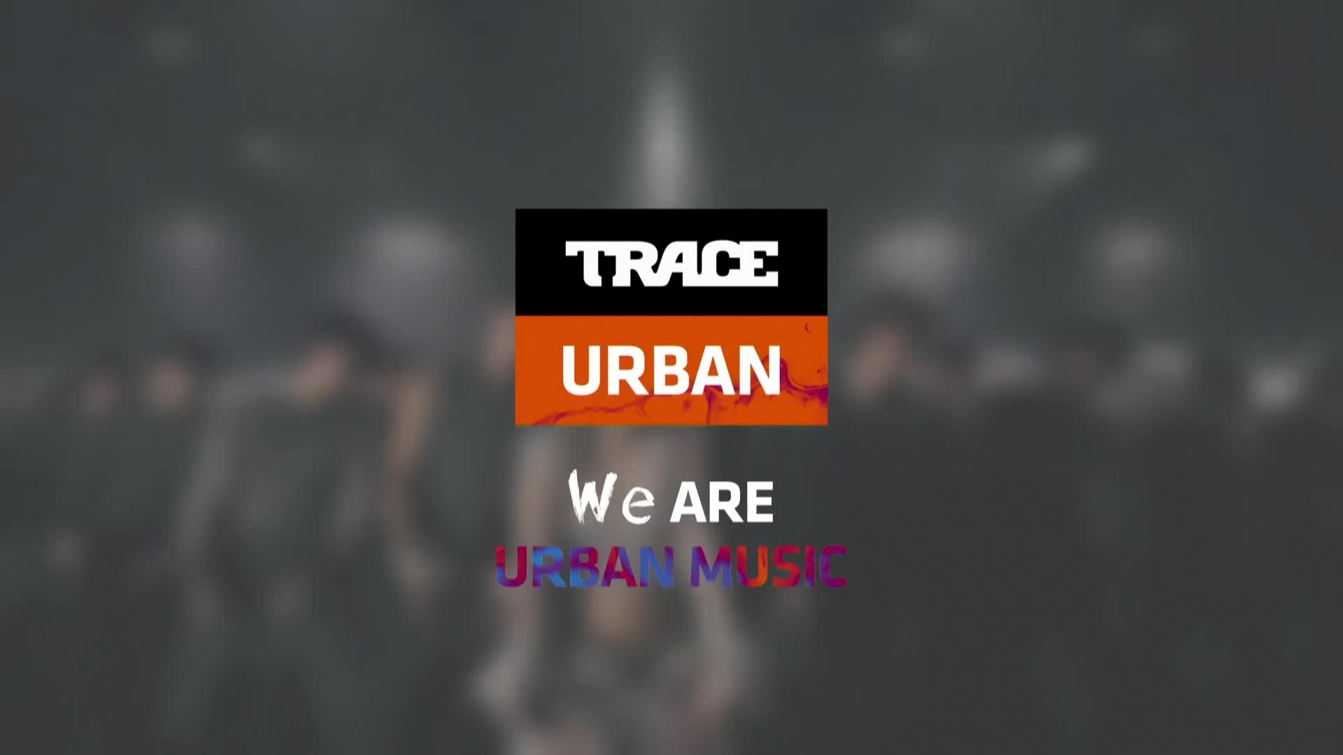 A group of people stand in a dimly lit space, their forms blurred. The Trace Urban logo, a bold orange and black rectangle, sits center frame. Below it, white text reads "We ARE" and then "URBAN MUSIC" in a vibrant, multicolored gradient.