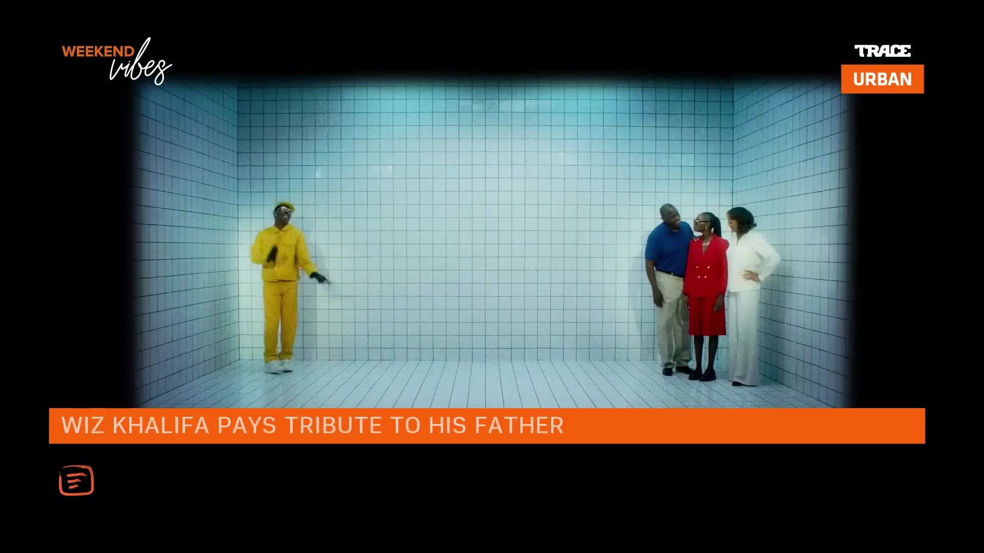 A rapper in a bright yellow tracksuit stands in a tiled room, facing away from three people in formal attire. The Trace Urban logo appears in the corner, and text below reads "Wiz Khalifa Pays Tribute to His Father."