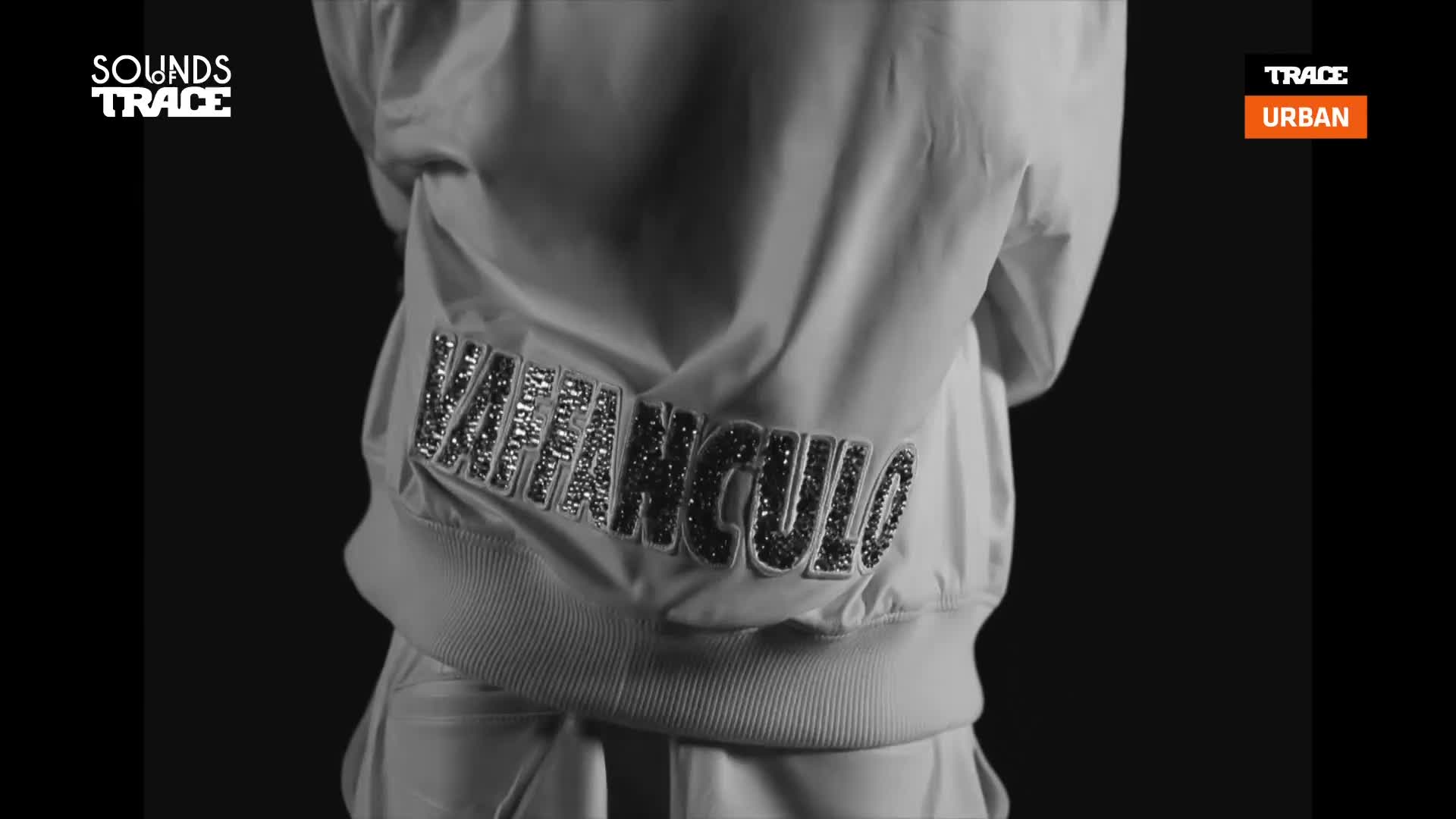 A white bomber jacket with "VAVANGULO" spelled out in sparkling letters is the focus. The Trace Urban logo appears in the corner, hinting at a French urban music scene. A white bomber jacket with "VAVANGULO" spelled out in sparkling letters is the focus. The Trace Urban logo appears in the corner, hinting at a French urban music scene.