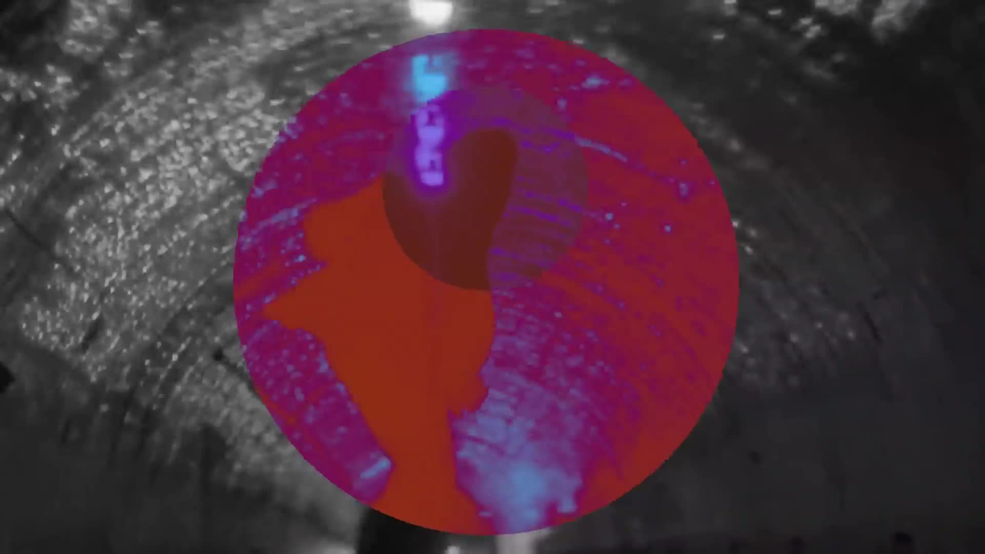 A circular projection of vibrant colors splashes across the rough, textured walls of a tunnel. The light shifts, casting an almost electric glow on the concrete, hinting at a performance or event happening within this Parisian underpass. A circular projection of vibrant colors splashes across the rough, textured walls of a tunnel. The light shifts, casting an almost electric glow on the concrete, hinting at a performance or event happening within this Parisian underpass.