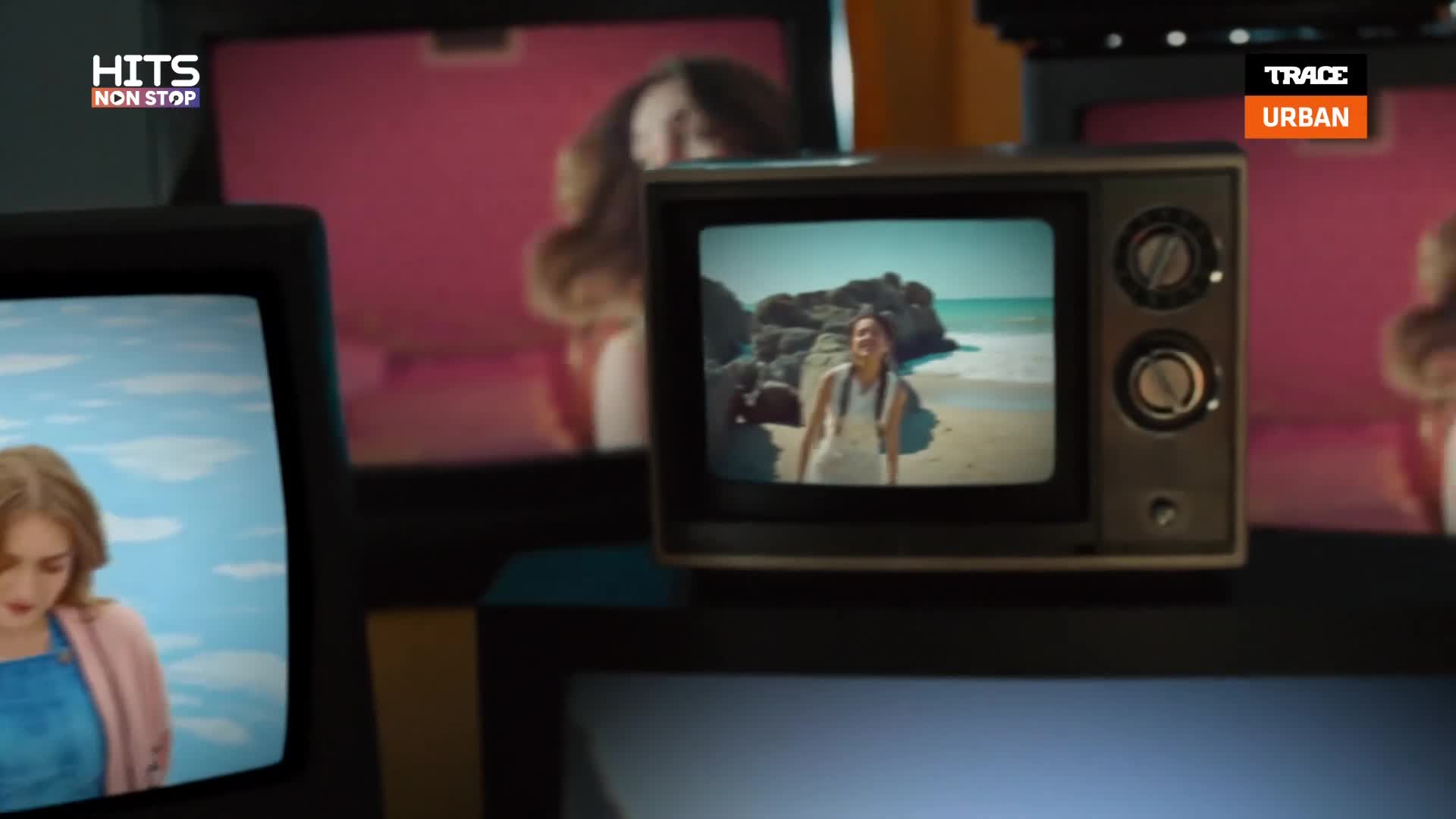 On a small screen, a woman in a white dress smiles on a rocky beach. Another screen to the left shows a woman looking down, framed by a bright blue sky. The Trace Urban logo is visible in the top right corner. On a small screen, a woman in a white dress smiles on a rocky beach. Another screen to the left shows a woman looking down, framed by a bright blue sky. The Trace Urban logo is visible in the top right corner.