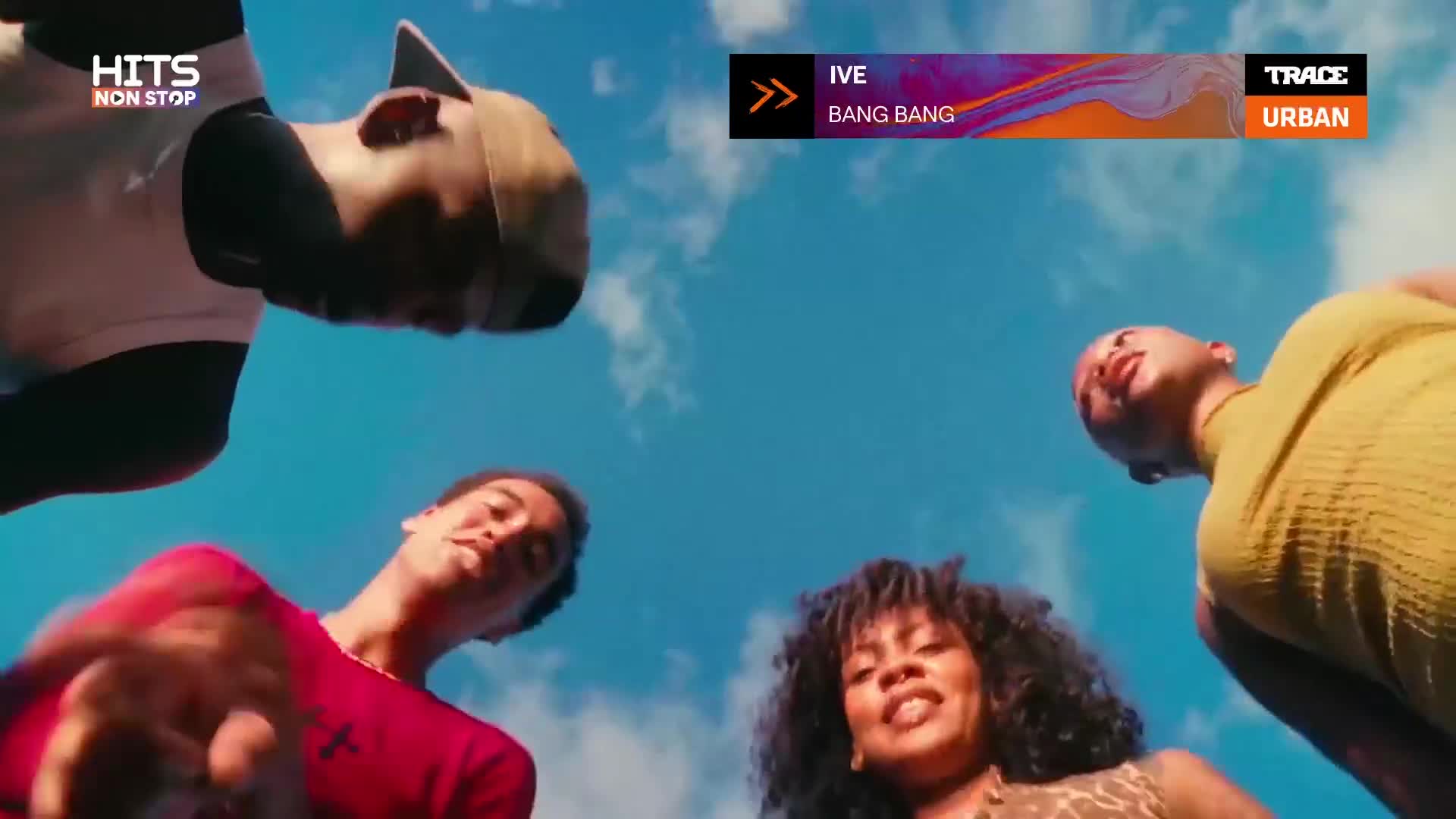 A group of young people lean in, their faces framed by a bright blue sky. The Trace Urban logo appears on screen as the song "Bang Bang" by IVE plays.