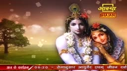 On the screen, a serene image of Radha and Krishna from Indian tradition is displayed, with the "Aastha Bhajan" logo prominently featured. The background shows a tranquil landscape, and the bottom of the screen displays text in Hindi.
