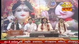 Four men sit behind instruments, performing in front of a backdrop of a deity, likely for an Aastha Bhajan broadcast from India. The musicians play and sing, their performance framed by the show's logo.
