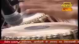 A hand strikes the tabla, the skin vibrating with each tap. A microphone hovers close, capturing the sound for the Aastha Bhajan broadcast in India.
