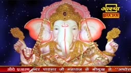 A large, ornate statue of Ganesha dominates the screen, his white trunk and tusks standing out against a backdrop of stars. The Aastha Bhajan logo sits in the corner, and text scrolls across the bottom.
