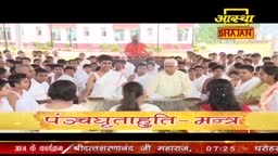 In a large group, people in white garments are gathered, with a man in red standing above them. The scene is broadcast on Aastha Bhajan, and the words "Panchghrutahuti- Mantra" are displayed on the screen.
