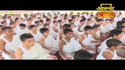 A large group of people in white clothing sit cross-legged, facing forward. The logo for Aastha Bhajan is visible in the top right corner.
A large group of people in white clothing sit cross-legged, facing forward. The logo for Aastha Bhajan is visible in the top right corner.