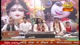 A man with long hair sings into a microphone, while others play instruments and accompany him. Behind them, a large image of Krishna adorns the backdrop of this Aastha Bhajan performance in India.

