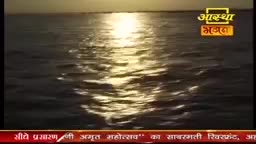 The sun's reflection shimmers on the water's surface, creating a golden pathway. The Aastha Bhajan logo is visible in the upper right corner, and text in Hindi is at the bottom of the screen.
