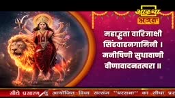 A goddess with multiple arms stands atop a majestic lion, its mane ablaze with light. This devotional image, likely from India, is presented on a screen with text in Hindi.