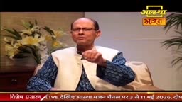 A man in a white vest over a patterned blue kurta gestures with his right hand. He speaks directly to the camera, a bouquet of lilies behind him.