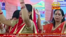A woman in a red sari raises her hands, her face turned upwards in devotion. Another woman beside her, also in a red sari, mirrors the gesture with her own hands lifted.