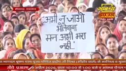 A woman holds up a sign in Hindi, surrounded by a crowd of people. The sign reads, "Don't go yet, Bhole Baba, my heart is not yet full."