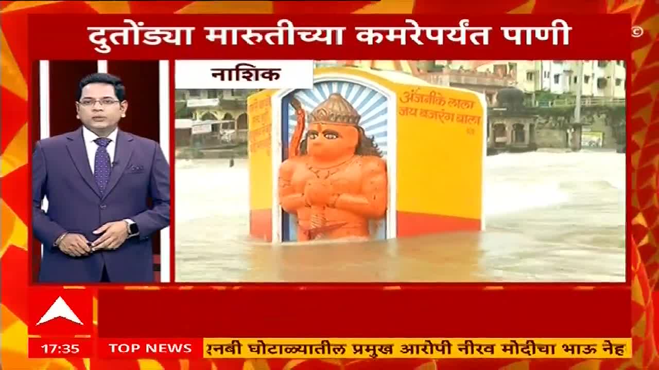 The orange statue of Hanuman stands submerged in the water, the flood reaching its waist. A news anchor on ABP Majha reports on the situation in Nashik, India.
