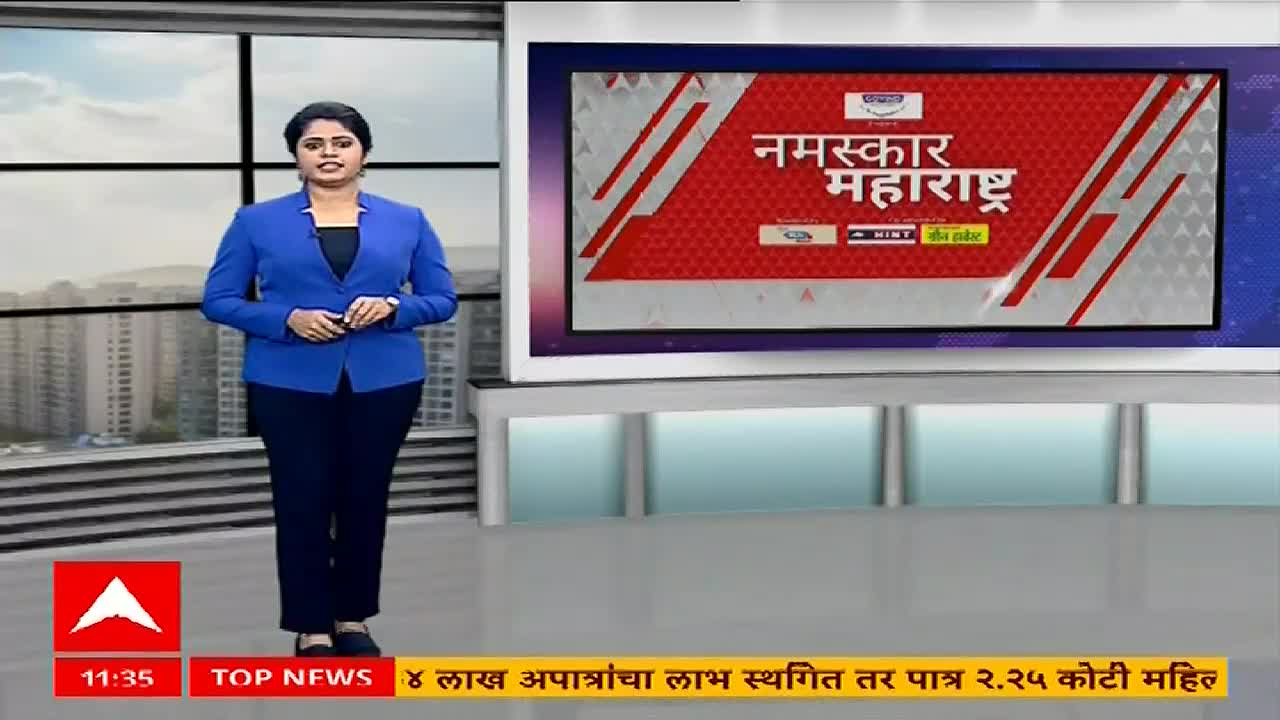 A woman in a blue blazer and dark pants stands in front of a large screen displaying "Namaskar Maharashtra" from ABP Majha. The news anchor is holding a microphone, ready to deliver the day's top stories.
