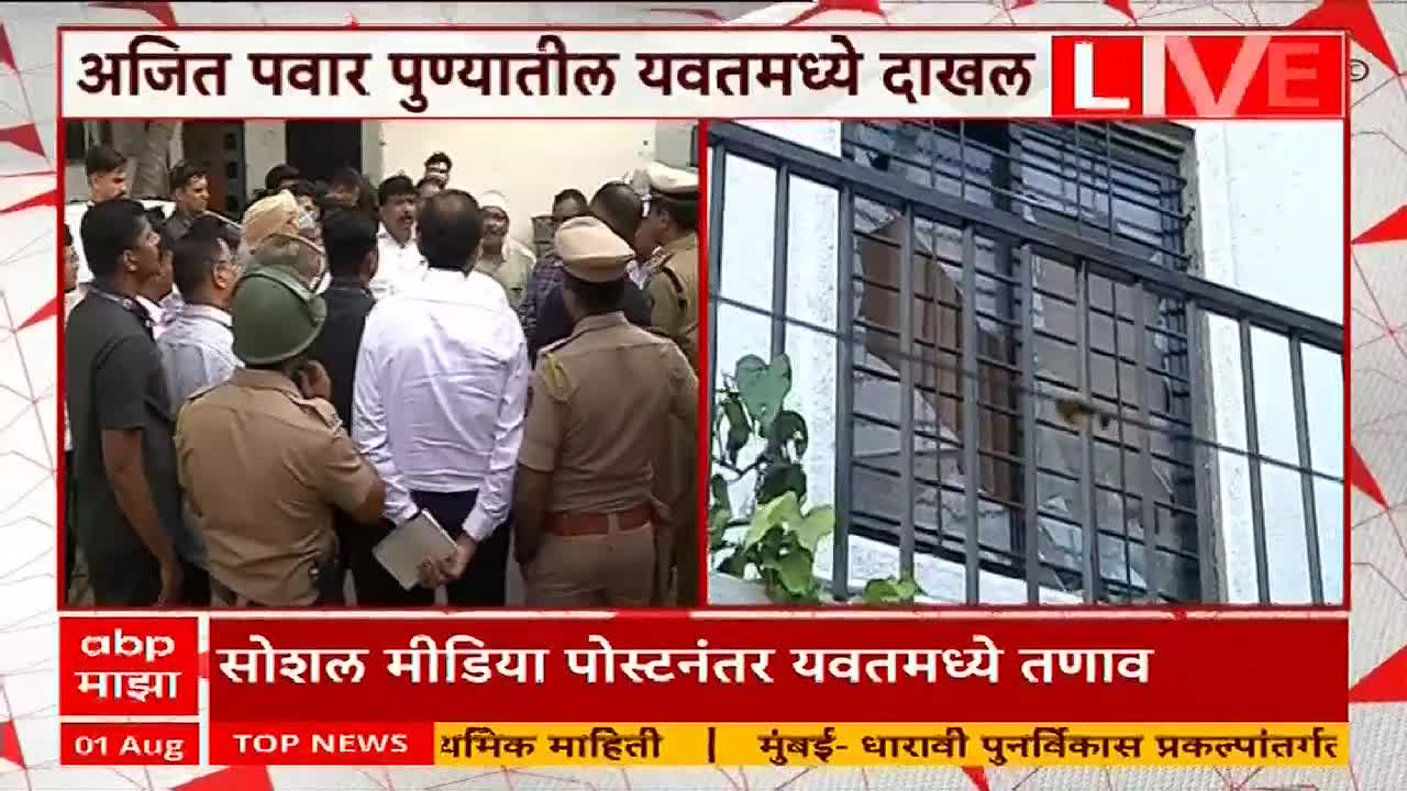A crowd of people, including several in what appear to be police uniforms, stand clustered outside a building. The window of the building has been smashed, visible on the right side of the screen, as ABP Majha reports live from Yavat, India.
