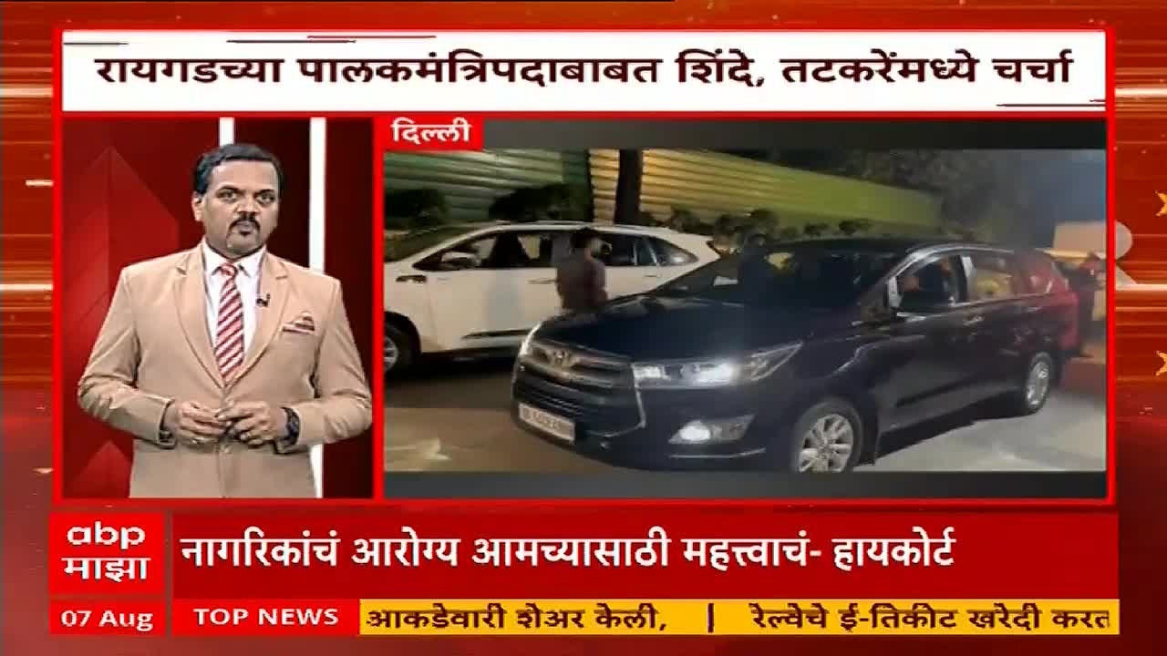 A news anchor in a tan suit is speaking on ABP Majha, while a black car pulls up next to a white one in Delhi. People are milling around near the vehicles, and it looks like a report is about to begin.
