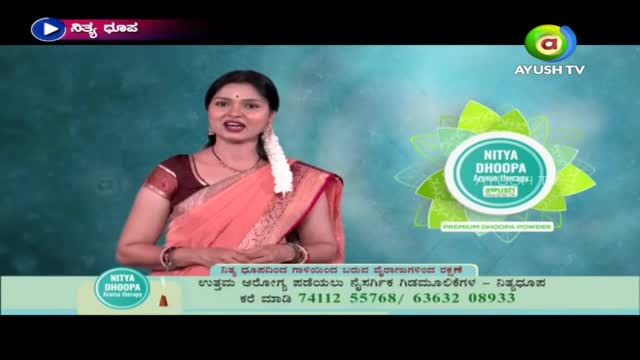 A woman in a sari stands in front of a teal background, speaking directly to the camera. Behind her, the Ayush TV logo and a graphic for "Nitya Dhoopa" are visible.

