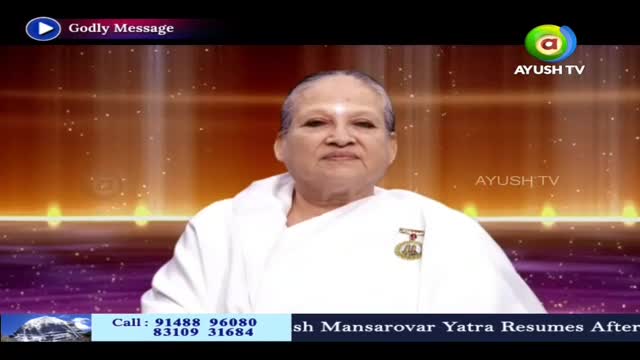 A woman in a white robe is centered, looking directly at the camera. The Ayush TV logo is visible, and a lower third banner mentions the Mansarovar Yatra.
