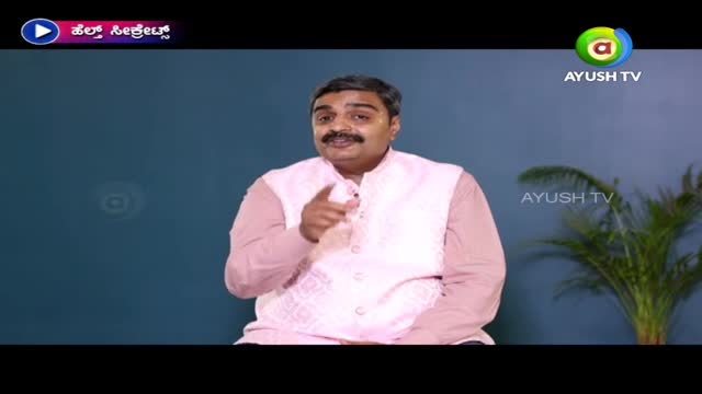 A man in a pink vest is speaking directly to the camera, pointing his finger. The Ayush TV logo is visible in the corner.
