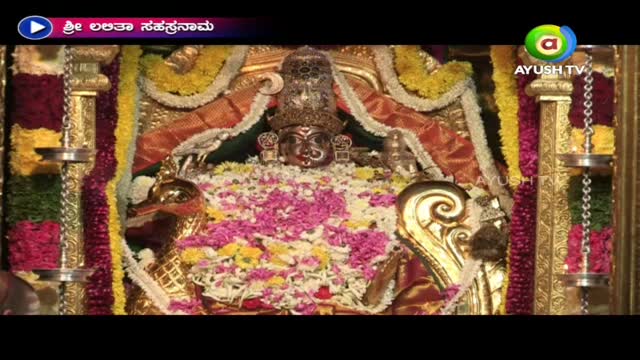 A golden idol rests amidst a vibrant bed of pink and white flowers, framed by ornate, gilded structures. This scene is broadcast on Ayush TV, with a title in Kannada.
