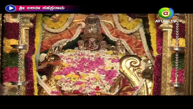 A deity, adorned with a jeweled crown, is surrounded by a vibrant array of flowers. The scene, broadcast by Ayush TV, is framed by ornate gold accents.
