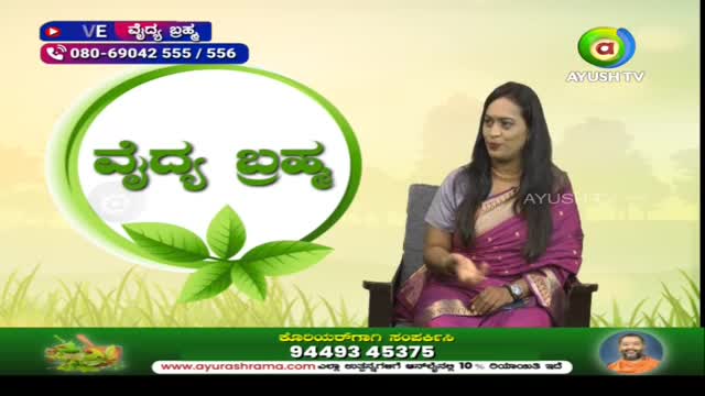 A woman in a pink sari is seated on a chair, speaking on a program for Ayush TV. The show's title, "Vaidya Brahma," is displayed in a large green circle.

