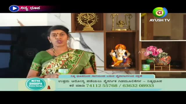 On Ayush TV, a woman in a green sari is speaking, holding a small cup. Behind her, a shelf displays religious figurines and a vase of flowers.

