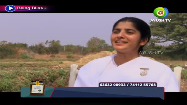 A woman in a white top is speaking, her face lit by the sun. The Ayush TV logo is visible, and a phone number scrolls across the bottom of the screen.

