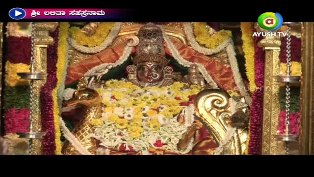 A decorated idol sits at the center, framed by garlands and ornate pillars. The Ayush TV logo in the corner indicates a broadcast from India.
