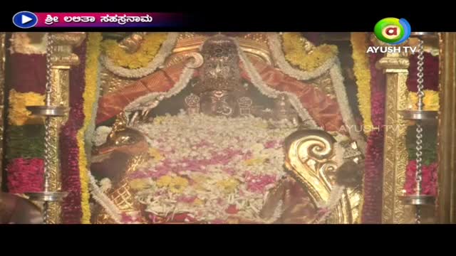 A golden structure sits in the center, surrounded by a profusion of flowers and garlands. The Ayush TV logo appears in the corner, indicating a broadcast from India.
