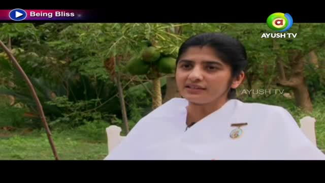 A woman in a white garment sits outdoors, speaking. The Ayush TV logo is visible in the corner.
