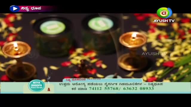 Small flames flicker atop ornate brass lamps, casting light on scattered flower petals. The Ayush TV logo is visible, and a banner below advertises Nitya Bhoopa Aroma Therapy.

