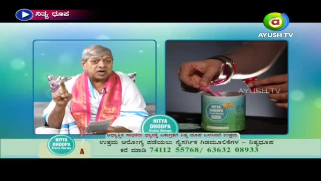 A man in a white robe and pink scarf gestures emphatically on Ayush TV, while a hand scoops a pink powder from a Nitya Dhoopa container. The screen shows a split-screen presentation about aroma therapy.
